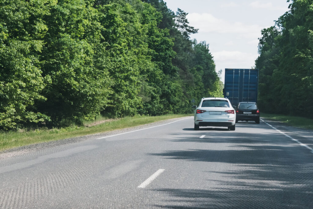 Two passenger cars make a double overtaking of a truck on a narrow road